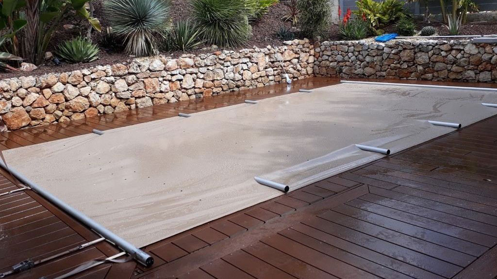 Propriétaire mesurant les dimensions de sa piscine avec mètre ruban le long de la margelle